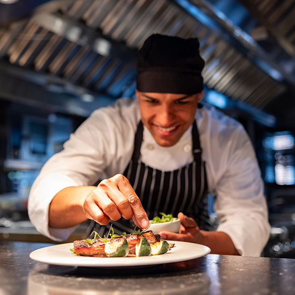 Smiling Chef Garnishing A Dish In A Kitchen